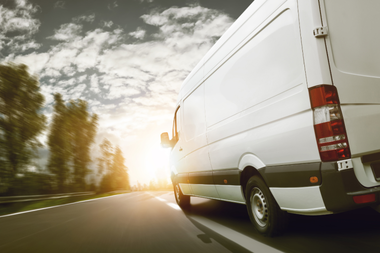 a white mercedes van on a road driving towards a sunset