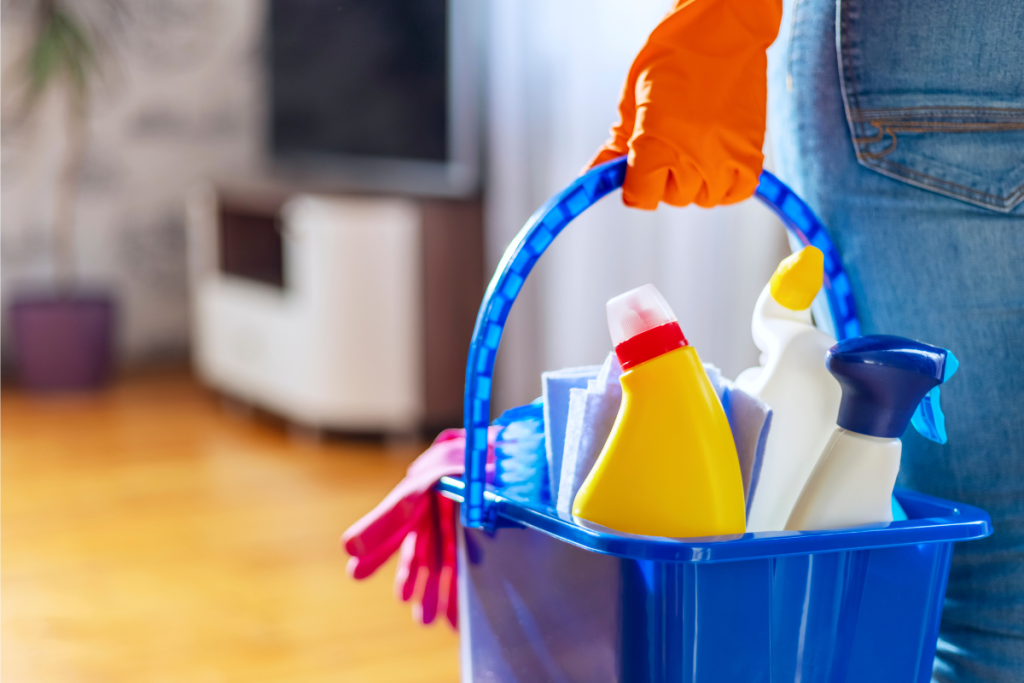 a person holding a bucket with cleaning equipment in it