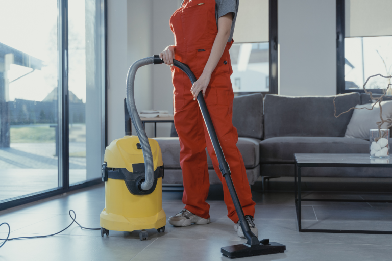 a cleaning person dressed in a red overall holding a vacuum cleaner