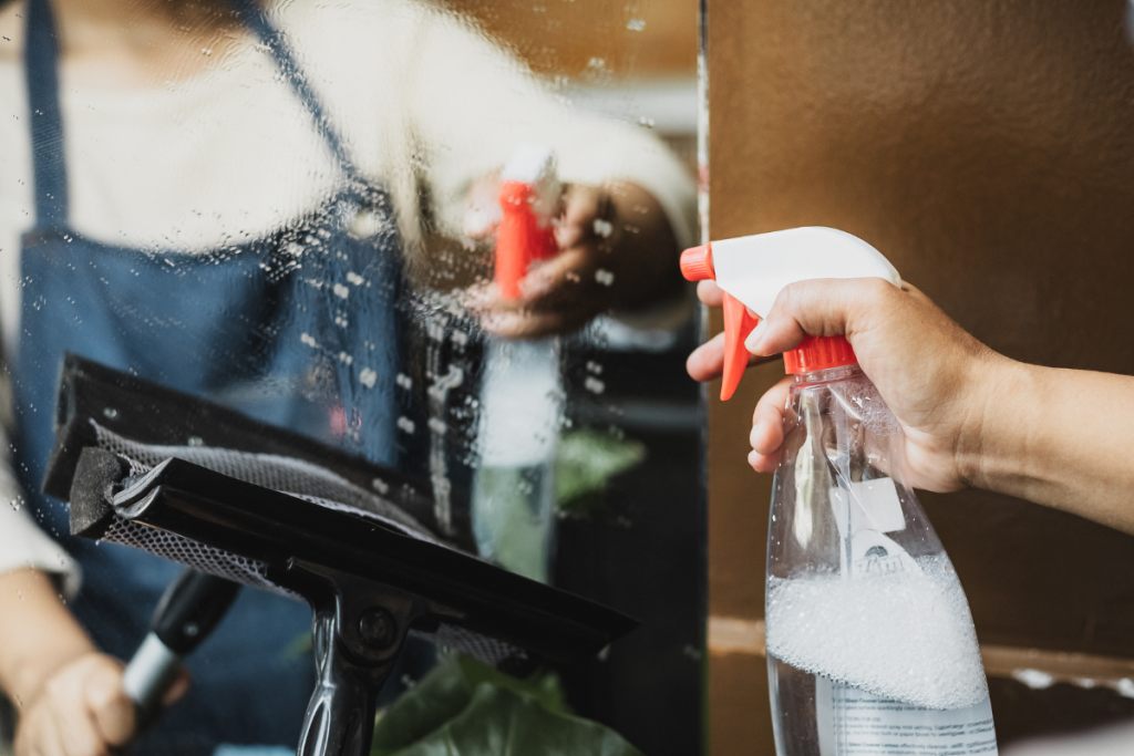 a person spraying cleaning fluid on a mirror